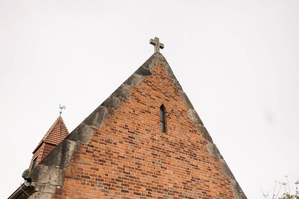 Giebel einer Backsteinkirche mit steinernem Kreuz.