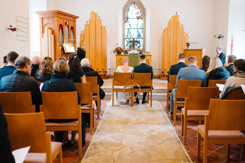 Hochzeitsgesellschaft im hellen Kirchenschiff.