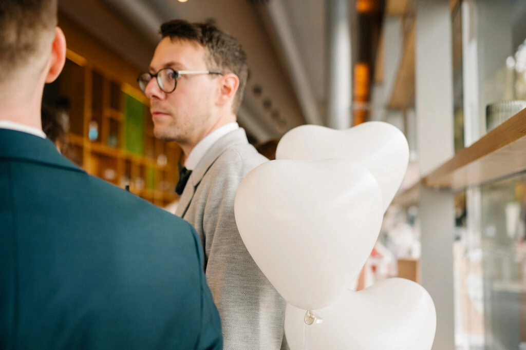 Hochzeitsgast mit weißen Herzballons im Restaurant.