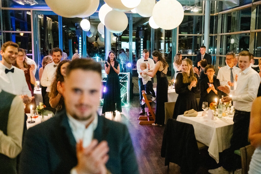 Hochzeitsgäste applaudieren im Festsaal.