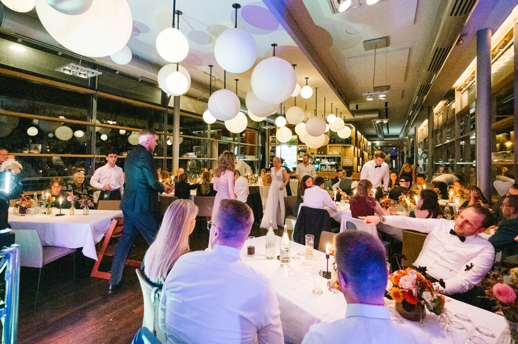 Hochzeitsgesellschaft im beleuchteten Restaurant am Abend.