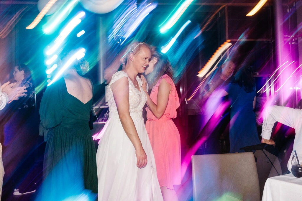 Braut und Gäste tanzen bei blauem Partylicht.