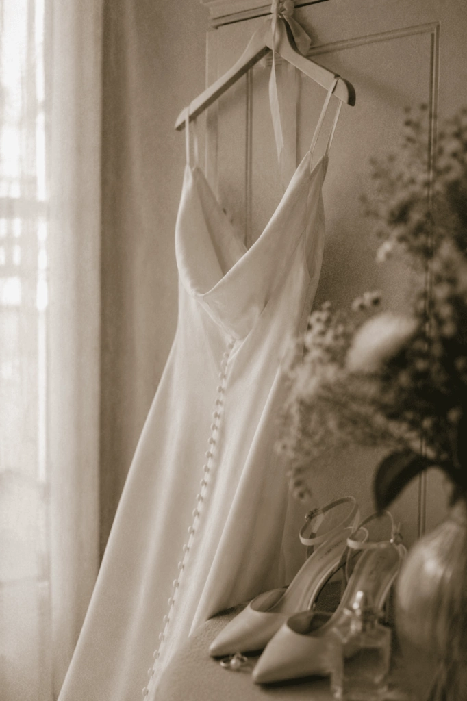 Weißes Brautkleid hängt neben einem hellen Fenster.