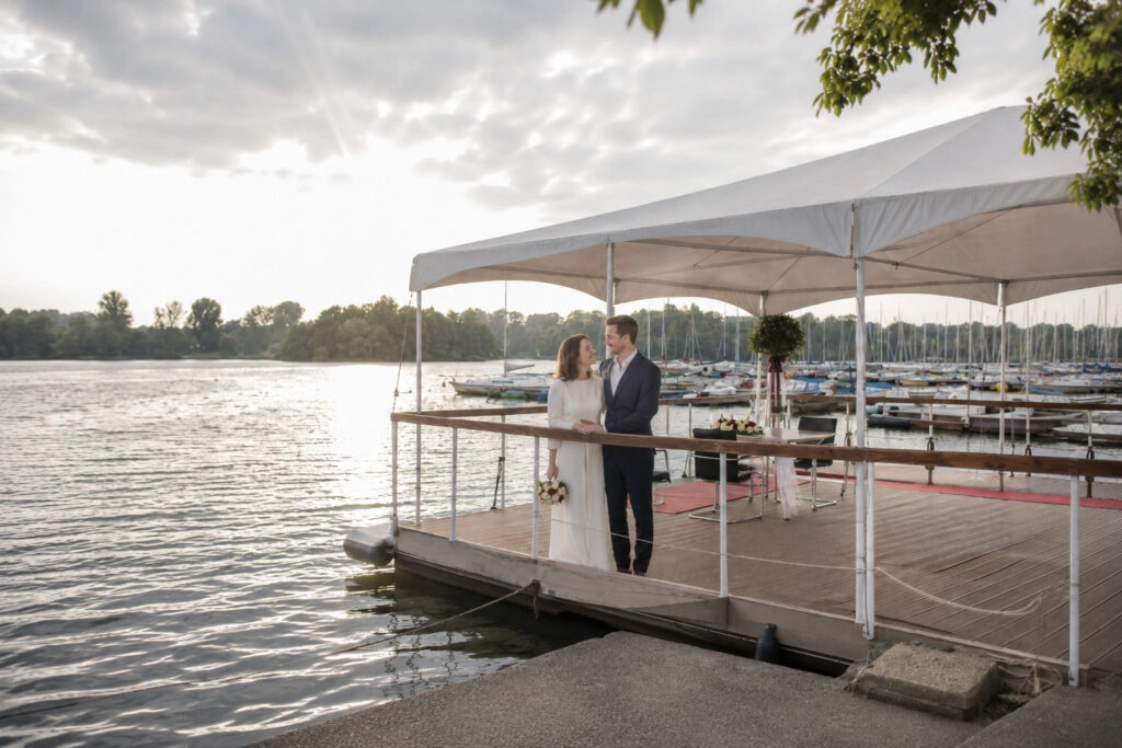 Weite Ansicht der überdachten Seeterrasse mit dem Brautpaar am Geländer.