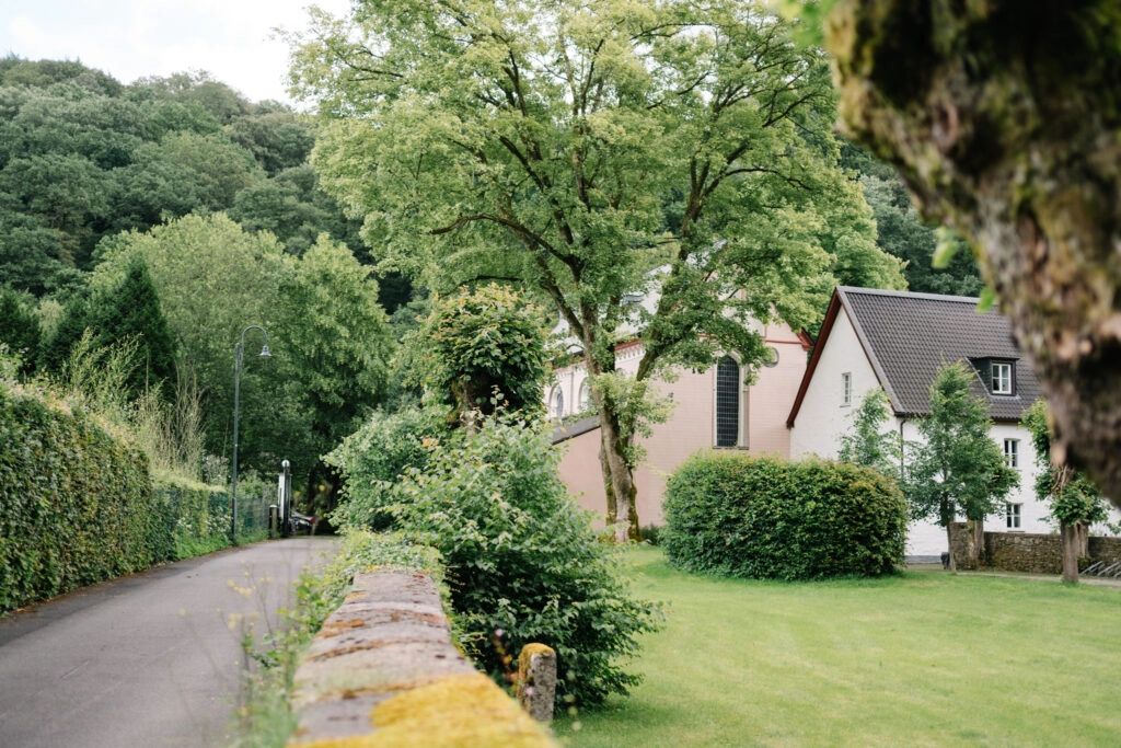Weg entlang einer kleinen Kirche im Grünen.
