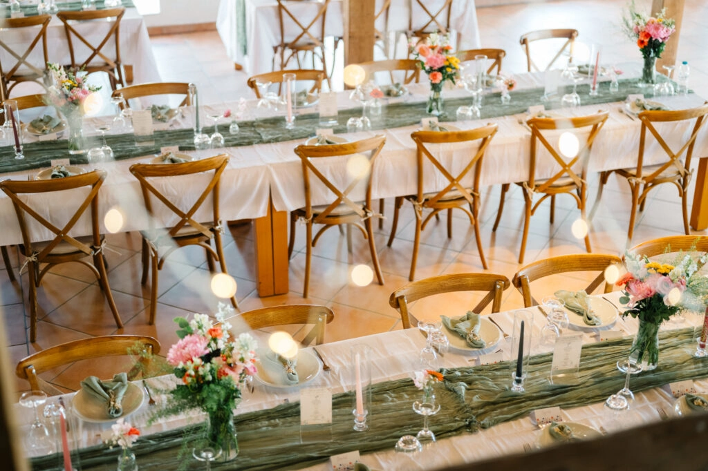 Festlich gedeckte Hochzeitstafel mit Blumen und Holzstühlen.