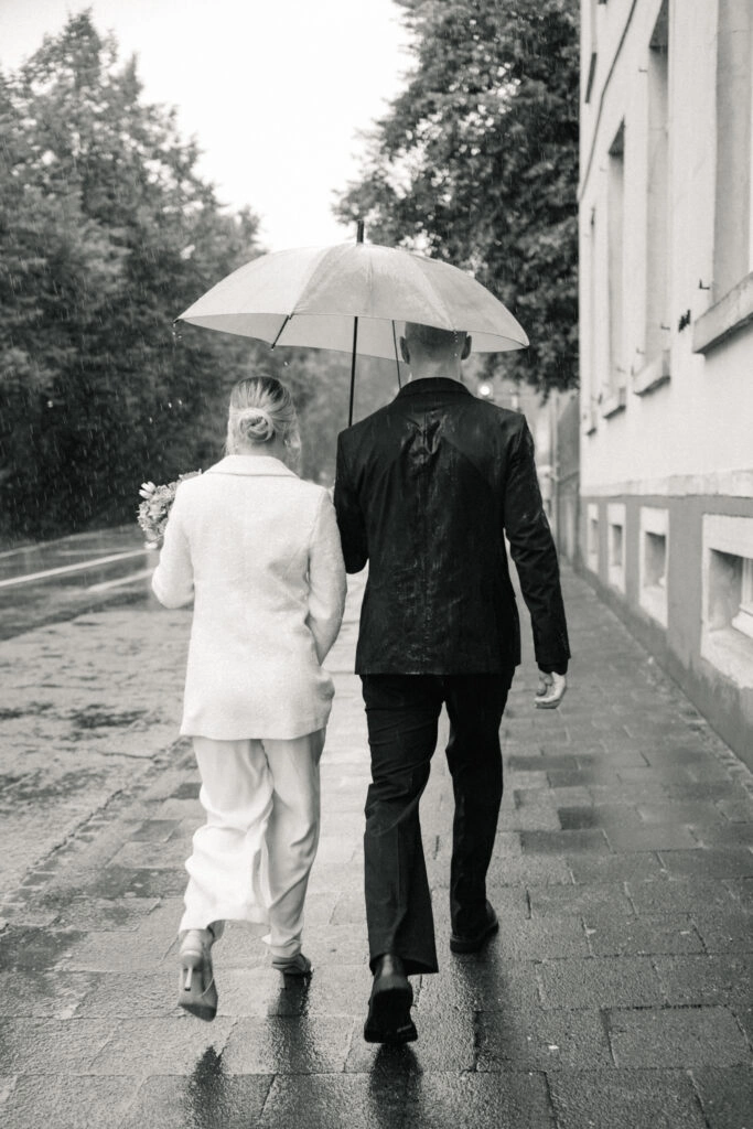 Brautpaar spaziert unter einem Regenschirm, in Schwarz-Weiß.