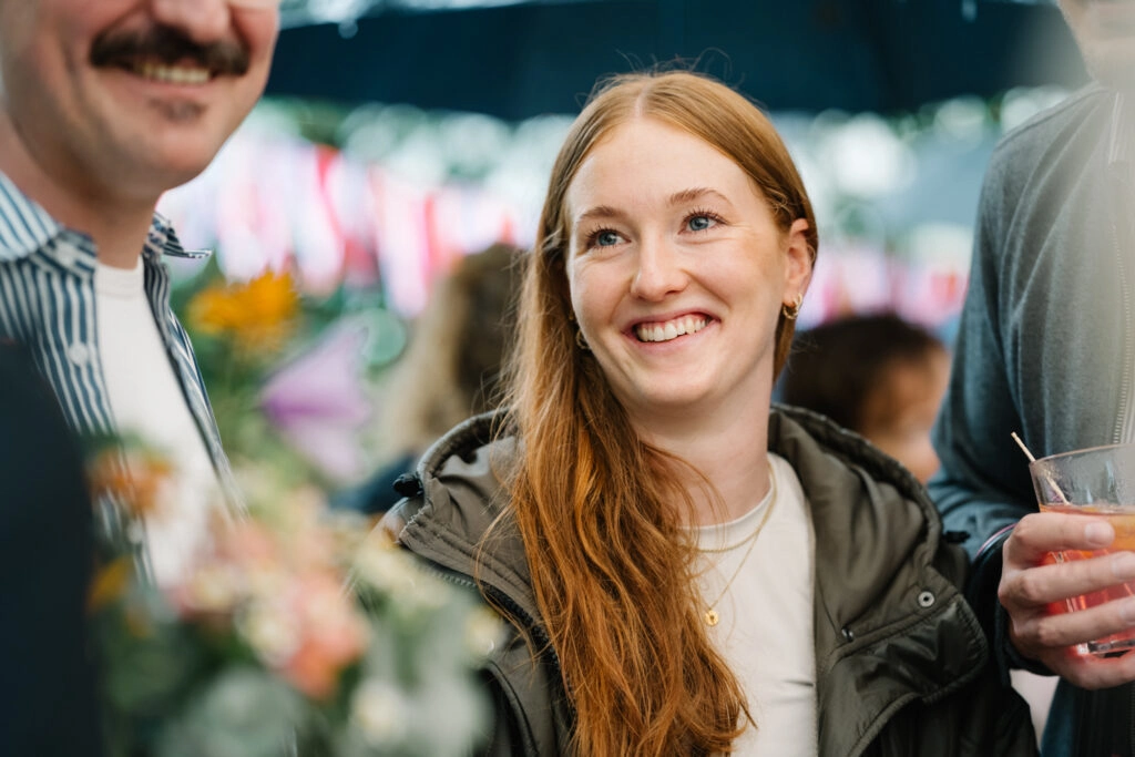 Gast lächelt zwischen Blumen und Hochzeitsgästen.