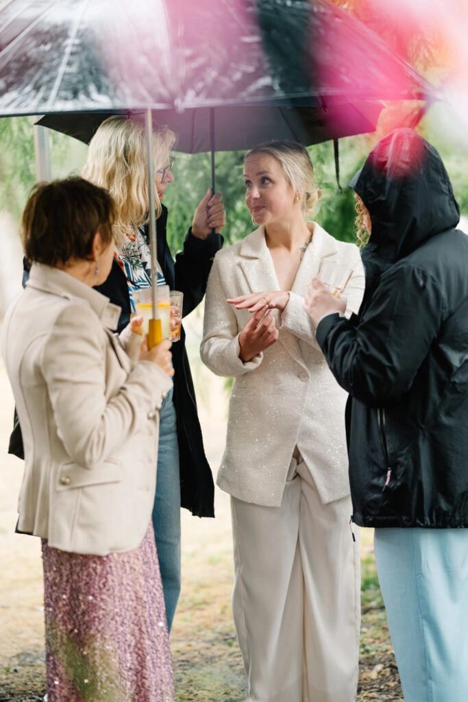 Braut unterhält sich mit Gästen im Regen.