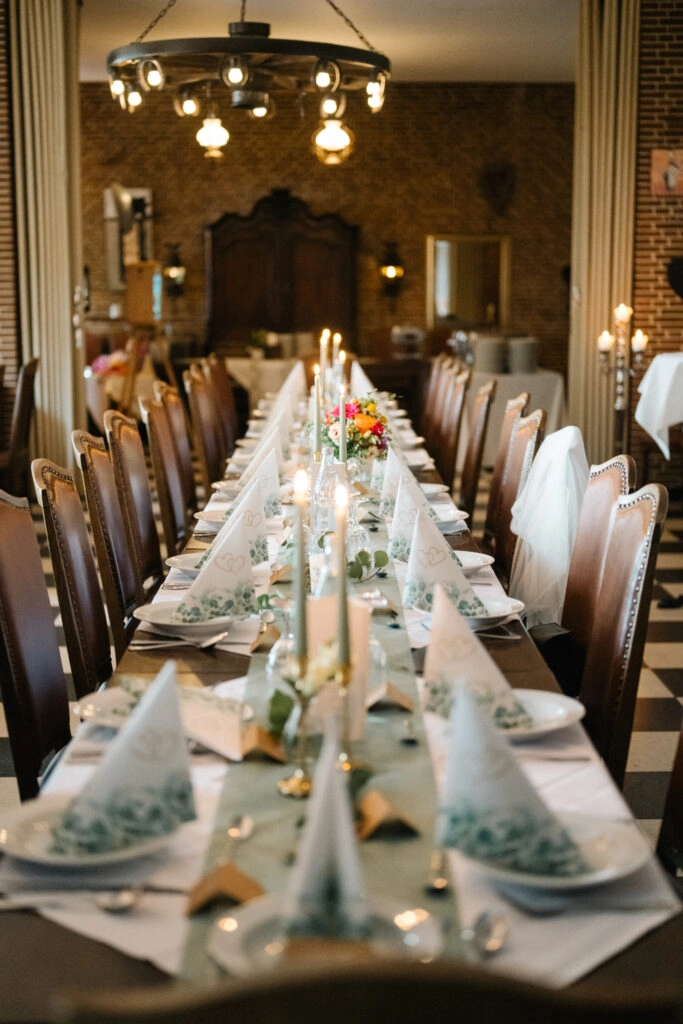 Lange gedeckte Tafel im warm beleuchteten Festsaal.