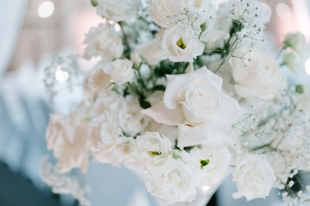 Weiße Rosen und helle Blüten in einem Hochzeitsgesteck.