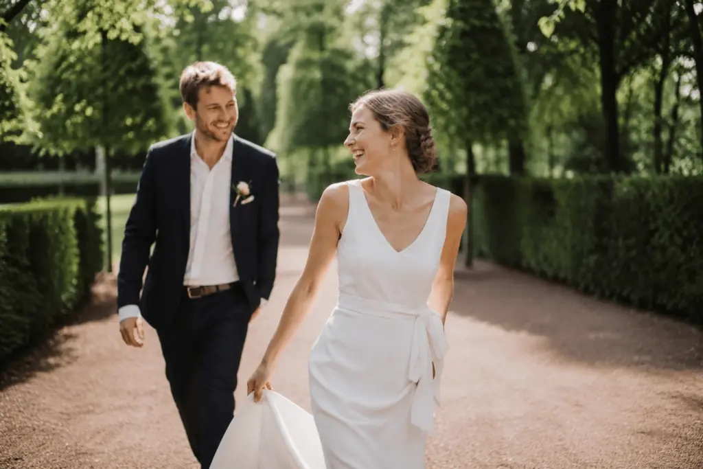 Lachendes Brautpaar Hand in Hand im Park von Schloss Benrath in Düsseldorf.